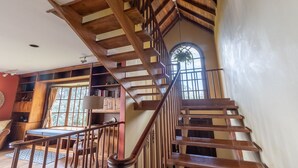 A wooden staircase with a view of a library and a window with a plant. - Stunning View of San Jose-private property on 2 acres, Casa Los Cielos & Studio  (Mata de Plátano)