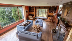 A spacious living room with a large window, a fireplace, and a wooden floor. - Stunning View of San Jose-private property on 2 acres, Casa Los Cielos & Studio  (Mata de Plátano)