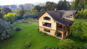 A two-story house with a balcony, surrounded by a well-maintained lawn and garden. - Stunning View of San Jose-private property on 2 acres, Casa Los Cielos & Studio  (Mata de Plátano)