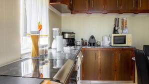 A kitchen with wooden cabinets, a stove, a microwave, and various appliances. - Fonte da Rosa Guest House APT2 (Belmonte)