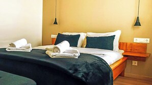 A neatly made bed with white and dark blue linens, two pillows, and a folded towel on the bed. - Fonte da Rosa Guest House APT2 (Belmonte)