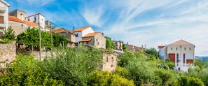 A hillside village with stone buildings, some with red-tiled roofs, and lush greenery.