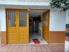 A residential entrance with a yellow door, a tiled floor, and a small red basket on the ground. - Merkezi Saray (Villavieja)
