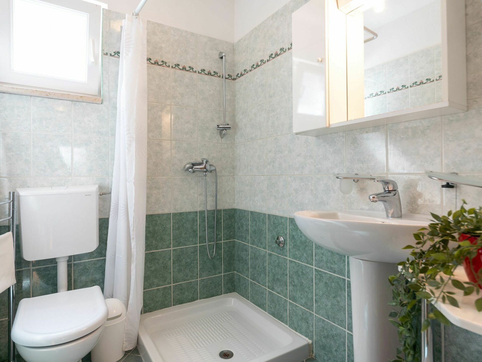 Une salle de bain avec douche, toilettes et lavabo.
