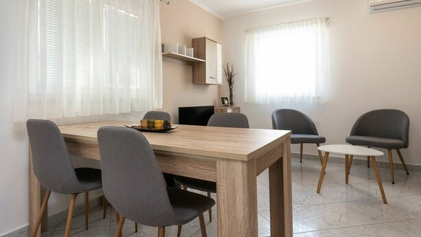 A dining area with a wooden table, four grey chairs, and a small white table. - Lovely apartment in villa for 5 guests with WIFI, A/C, TV and terrace (Umag)
