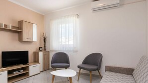 A modern living room with a flat-screen TV, two grey armchairs, a white coffee table, and a beige sofa. - Lovely apartment in villa for 5 guests with WIFI, A/C, TV and terrace (Umag)