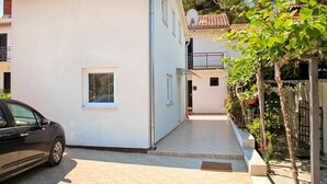 A narrow street with a white building, a parked car, and a tree with flowering branches. - Lovely apartment in villa for 5 guests with WIFI, A/C, TV and terrace (Umag)