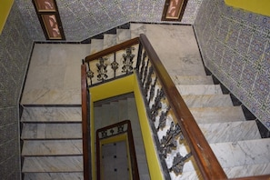 A marble staircase with intricate patterns on the walls and a wooden handrail.
