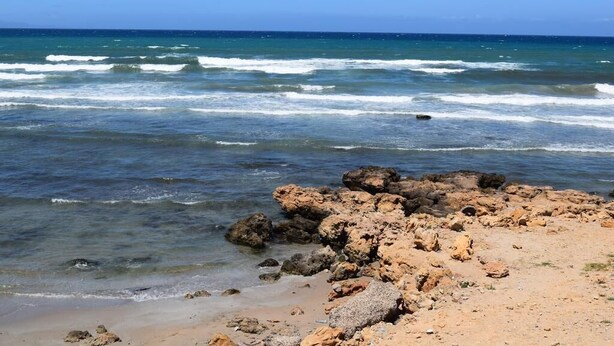 Ein felsiger Strand mit brechenden Wellen.