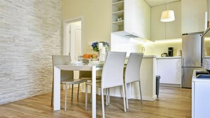 Eine moderne Küche mit weißen Schränken, einem Essbereich mit Tisch und Stühlen sowie einer Wand mit Steinverkleidung.