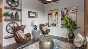 A modern living room with a high ceiling, exposed beams, and a mix of contemporary and rustic decor.
