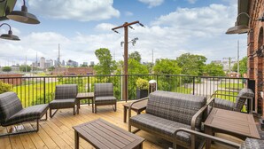 A wooden deck with wicker furniture and a view of a city skyline.