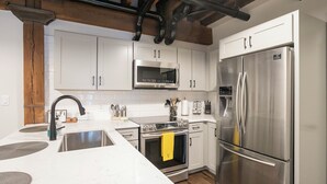 Une cuisine moderne avec des armoires blanches, des appareils en acier inoxydable et un plafond en bois.