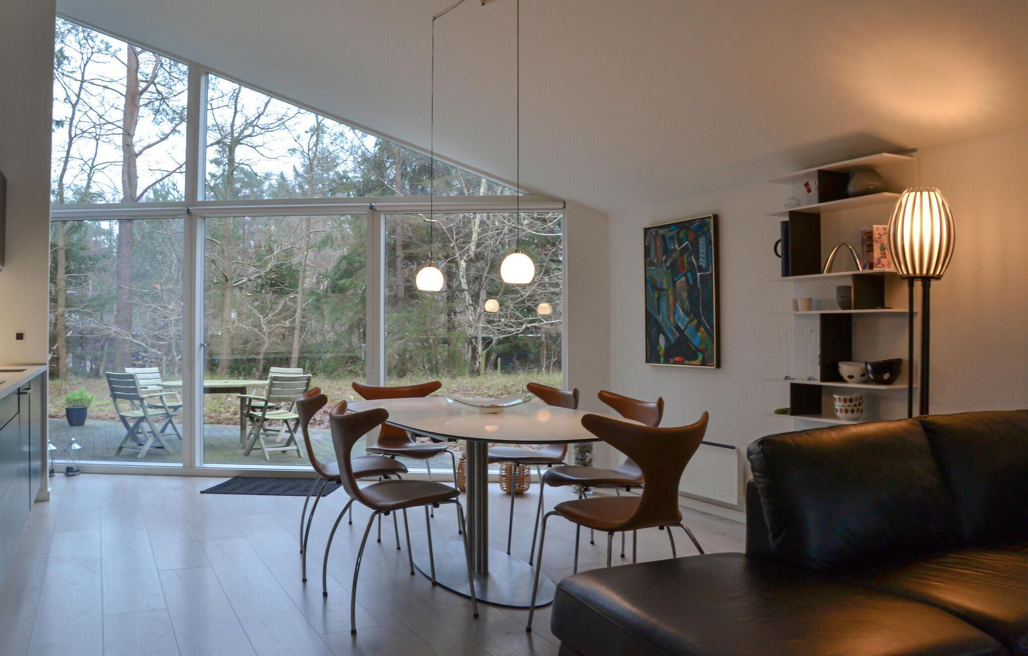 A modern interior with a dining area, a sofa, and a bookshelf.