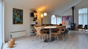 A modern dining area with a round table and chairs, a bookshelf, and a large abstract painting on the wall. - Amazing home in Græsted with kitchen (Græsted)