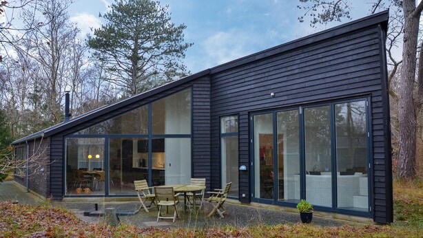 A modern house with large windows, a patio with a table and chairs, and a garden area. - Amazing home in Græsted with kitchen (Græsted)