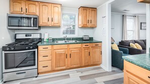 Una cocina moderna con armarios de madera, una estufa de acero inoxidable, un microondas y un fregadero.