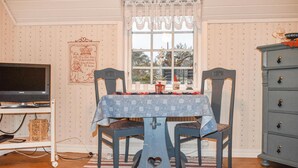 A dining area with a table, chairs, a television, and a dresser.