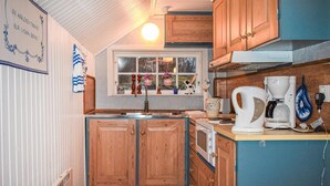 A kitchen with wooden cabinets, a sink, a stove, and a window with hanging flower pots.