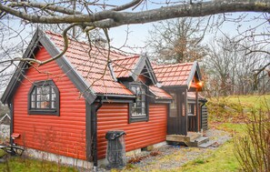 Une maison en bois rouge, avec un toit en pente et des bordures noires.