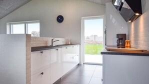 Una cocina moderna con armarios blancos, encimera negra y horno empotrado. Hay una ventana que ofrece vistas al exterior.