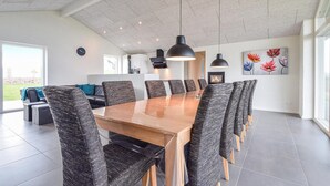 Un comedor moderno con una mesa de madera larga, varias sillas e iluminación colgante.