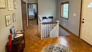 A hallway with a wooden floor, a round rug, and a staircase leading to a dining area.