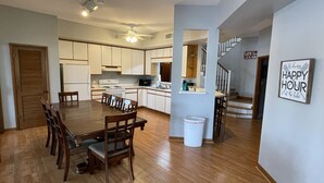 A modern kitchen with white cabinets, a dining table with chairs, and a staircase leading to another level.