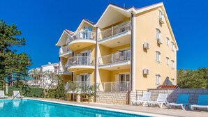 A multi-story hotel with balconies, a swimming pool, and lounge chairs.