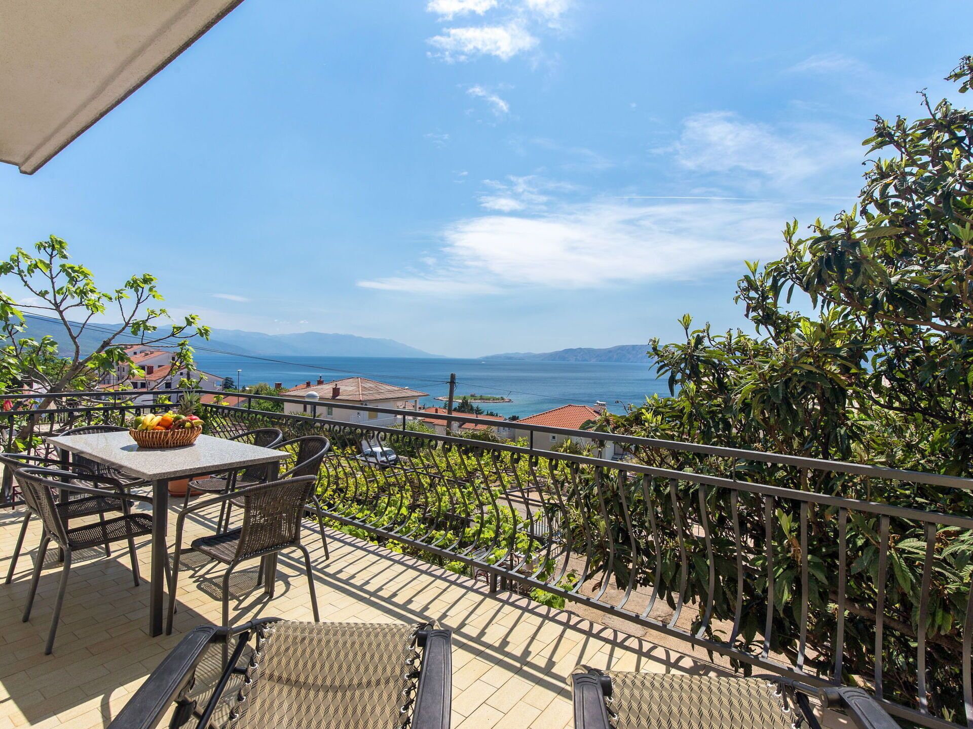 Ein Balkon mit Tisch, Stühlen und einer Obstschale.