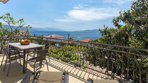 En balkon med et bord, stole og en frugtkurv.
