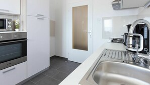 Et moderne køkken med rustfrie stålens hvidevarer, indbygget ovn og kaffemaskine.
