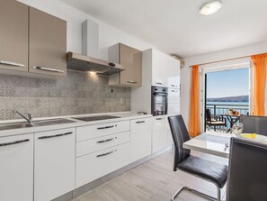 Enjoy meals in this kitchen with a stainless steel sink, oven, and range hood, adjacent to a dining area with a table and chairs.