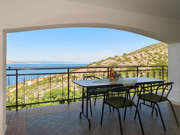 Enjoy the breathtaking view of the coastline from this balcony, featuring a table and chairs for a relaxing outdoor space.