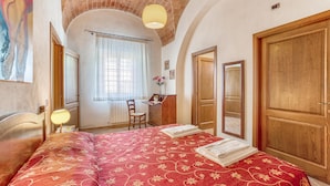 A hotel room with a bed, a desk, a chair, and a large wooden door. - Cozy home in Tavarnelle Val di Pesa with WiFi (Tavarnelle Val di Pesa)
