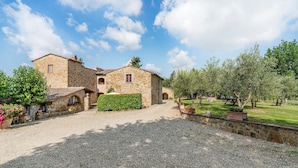 A stone building with a gravel driveway and a well-maintained garden with trees and shrubs. - Cozy home in Tavarnelle Val di Pesa with WiFi (Tavarnelle Val di Pesa)