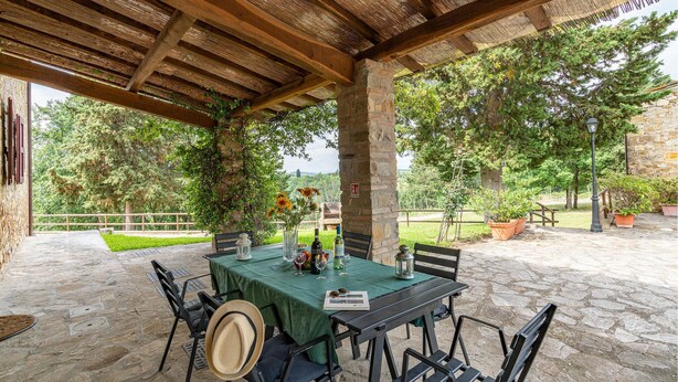 An outdoor patio with a stone floor, a table set with a green tablecloth, and chairs. - Cozy home in Tavarnelle Val di Pesa with WiFi (Tavarnelle Val di Pesa)