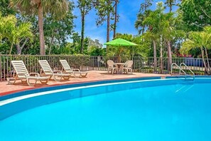 Un espace piscine avec des chaises longues et une table munie d’un parasol.