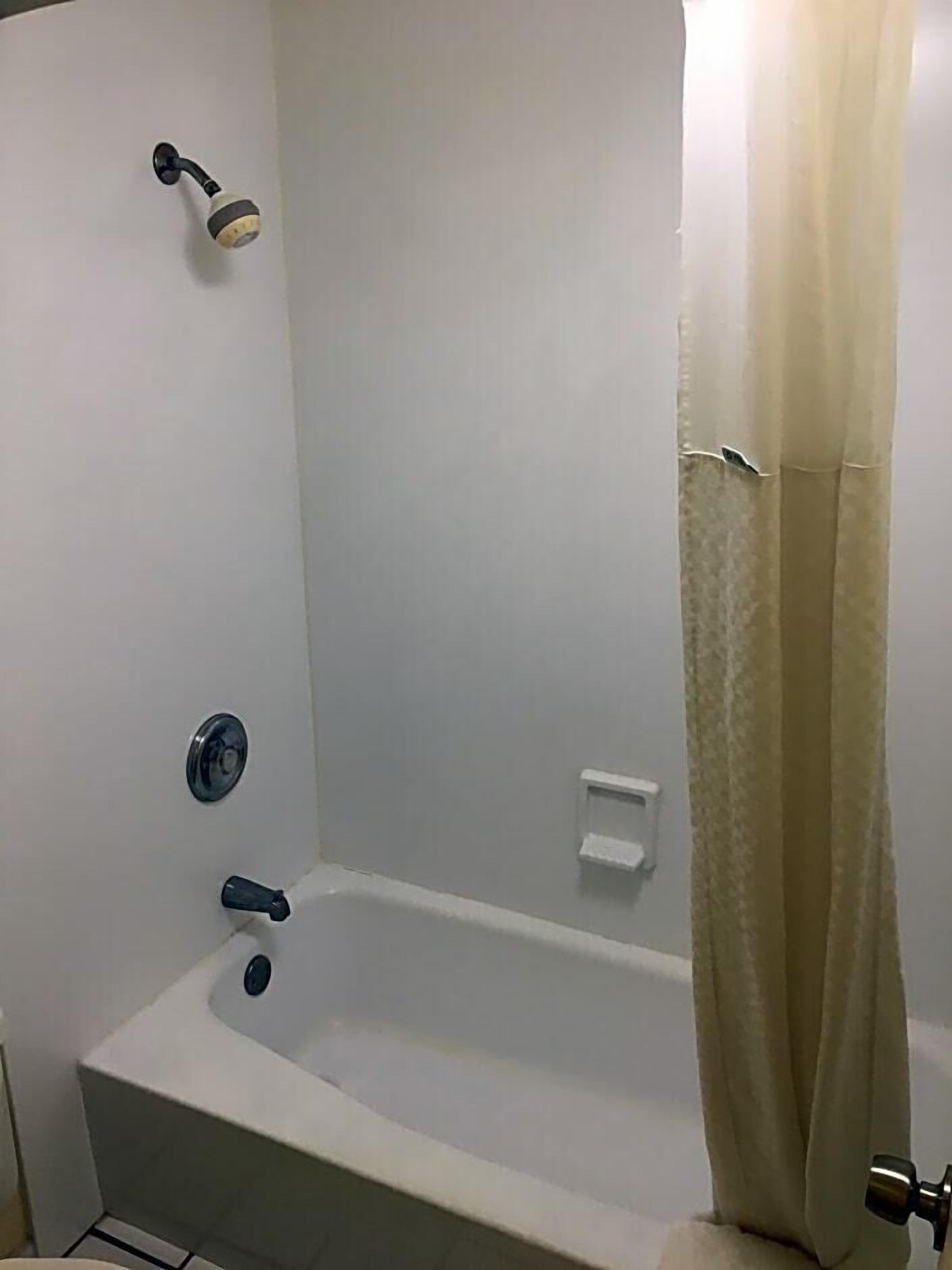 Et badeværelse med badekar, bruser og toilet.