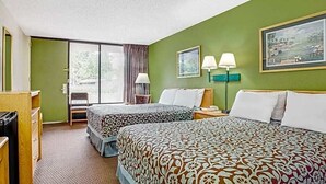Habitación de hotel con dos camas, un escritorio, una silla y una ventana con cortinas.