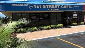 Café 1st Street con toldo azul y un letrero que indica que ofrece desayuno y almuerzo.