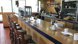 Una barra larga con taburetes, una zona de cocina y vistas al exterior.