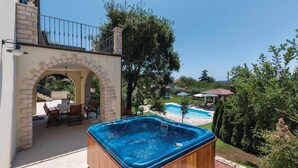 Een houten jacuzzi in een achtertuin met een zwembad en een terras.