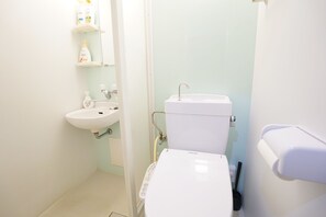 Une salle de bain avec des toilettes, un lavabo et une douche.