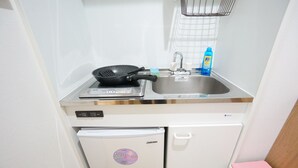 A compact kitchen with a stove, sink, and dishwasher. - Terry's Apartment Namba South V C01A (Osaka)