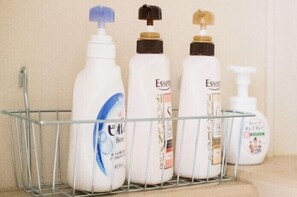 Une étagère de salle de bain avec trois flacons de produits de soins capillaires Essanté et un flacon de shampoing.