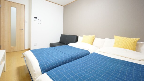 A hotel room with two beds, a desk, a chair, and a wardrobe. - Terry's Apartment Namba South V C01F (Osaka)
