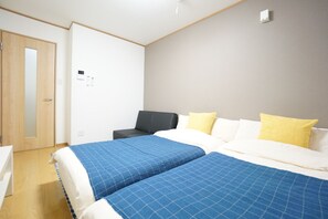 Een hotelkamer met twee bedden, een bureau, een stoel en een kledingkast.
