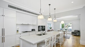 Una cocina moderna con armarios blancos, una isla central con taburetes y luces colgantes.