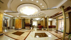 A spacious lobby with a central chandelier, marble flooring, and a seating area with red sofas. - Safran Hotel (Baku)